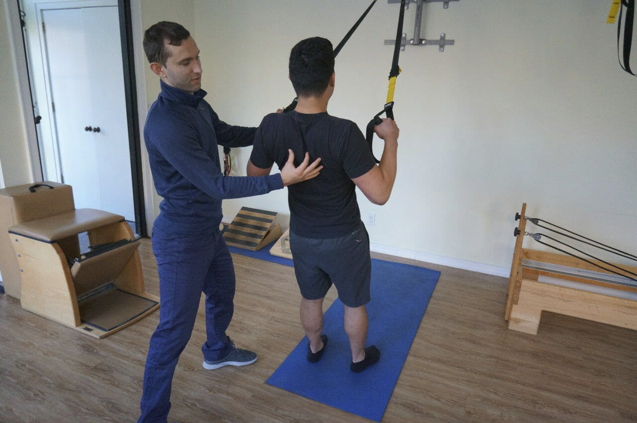 Igor Kozlov, DPT treating patient using TRX for back exercise
