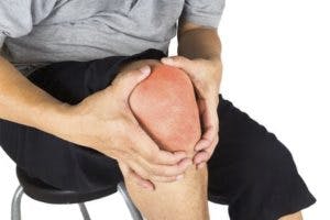 person with knee pain grasping knee
