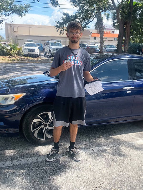 Young man driver holding up driver's license
