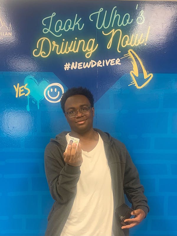 Young man driver holding up driver's license