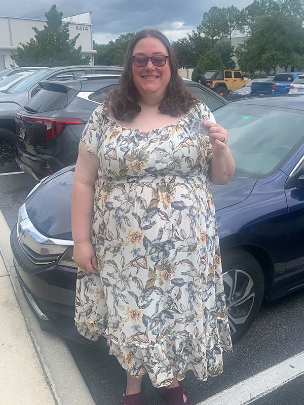 Middle-aged woman driver holding up driver's license
