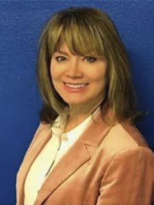 Cindy Greenfield, PT, wearing a tan jacket over a white shirt in front of a blue background