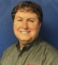 Daryl Greenfield, CRT, wearing a gray button down in front of a blue background